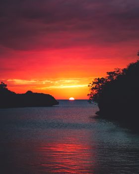 平静的大海上，迷人的日落映照着天空，色彩鲜艳，橙色与红色交织