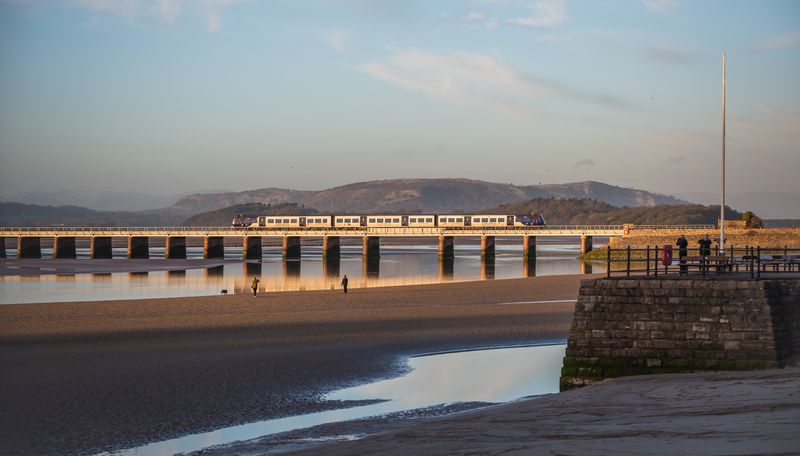 Passenger train crossing a coastal viaduct at golden hour — photo by Christopher Kirk on Pexels