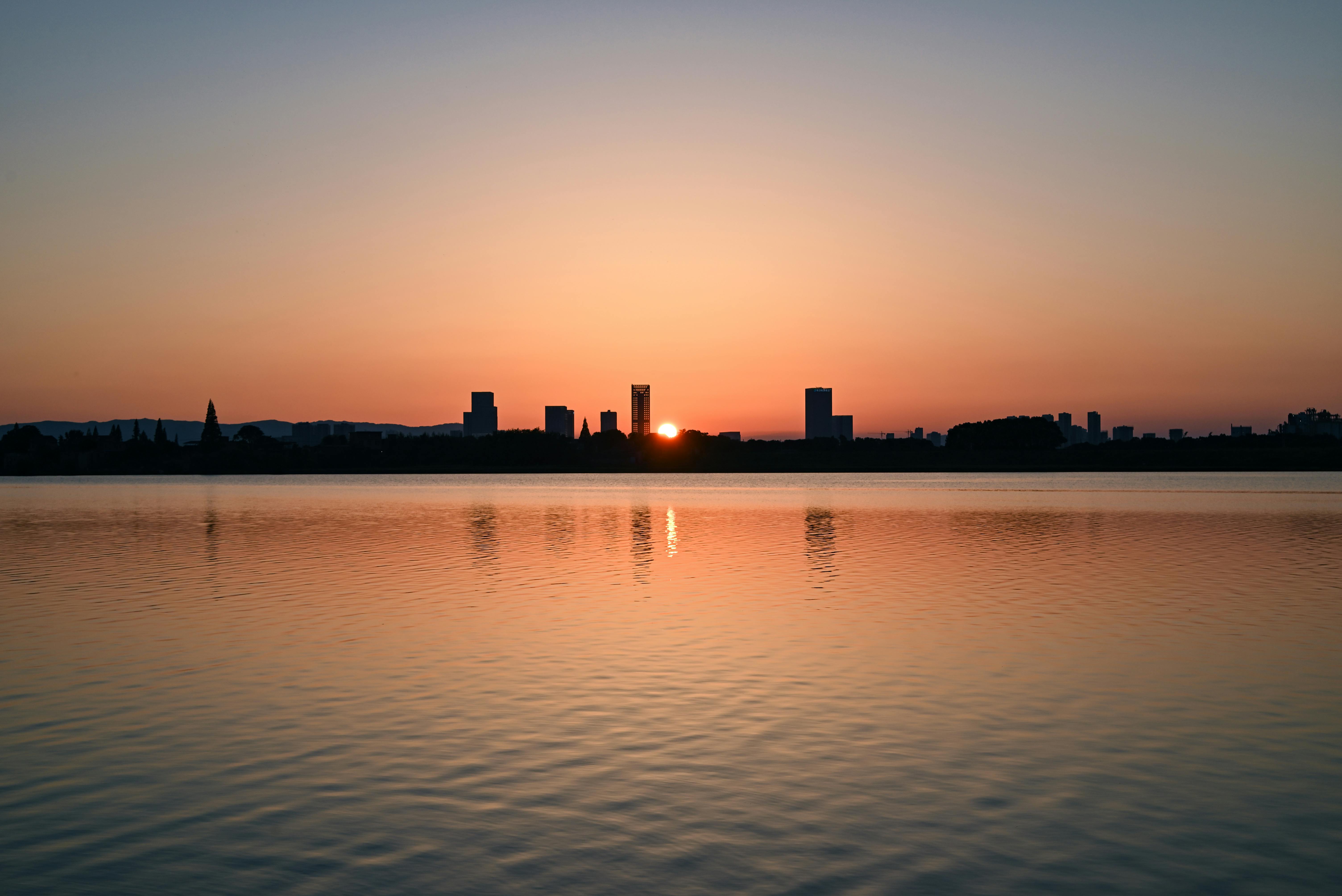 ingyenes Városkép sziluettje, festői naplementével a vízen. Stockfotó