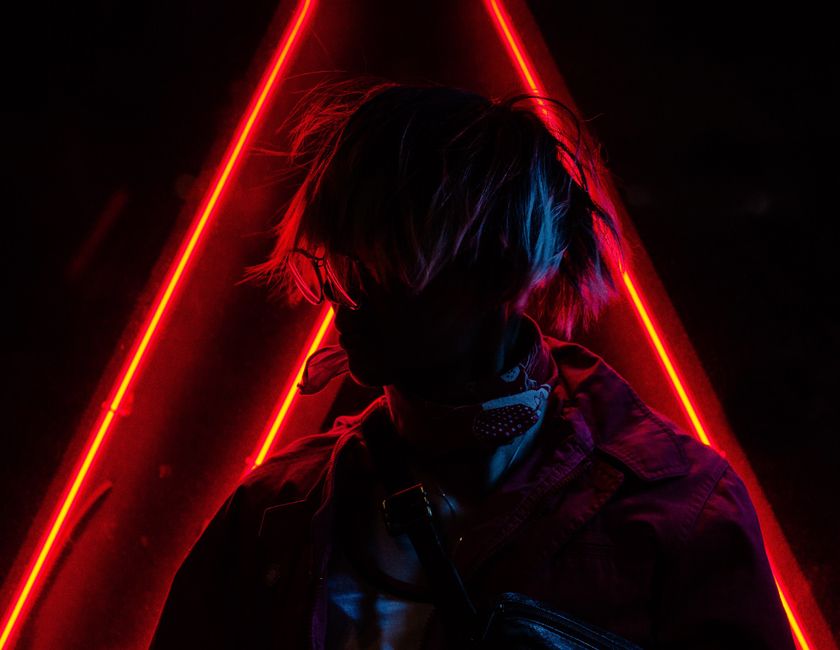A fashionable silhouette of a person posing against vibrant red neon lights.