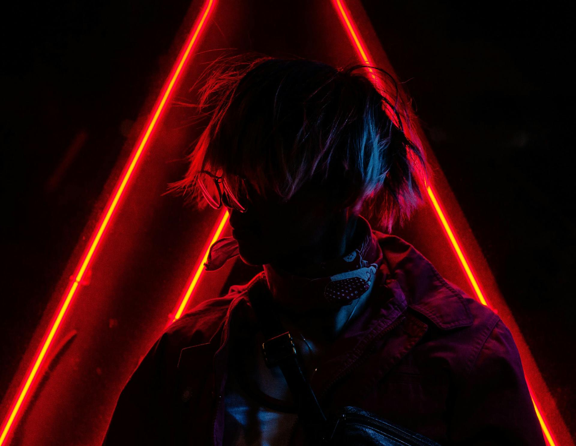 A fashionable silhouette of a person posing against vibrant red neon lights.