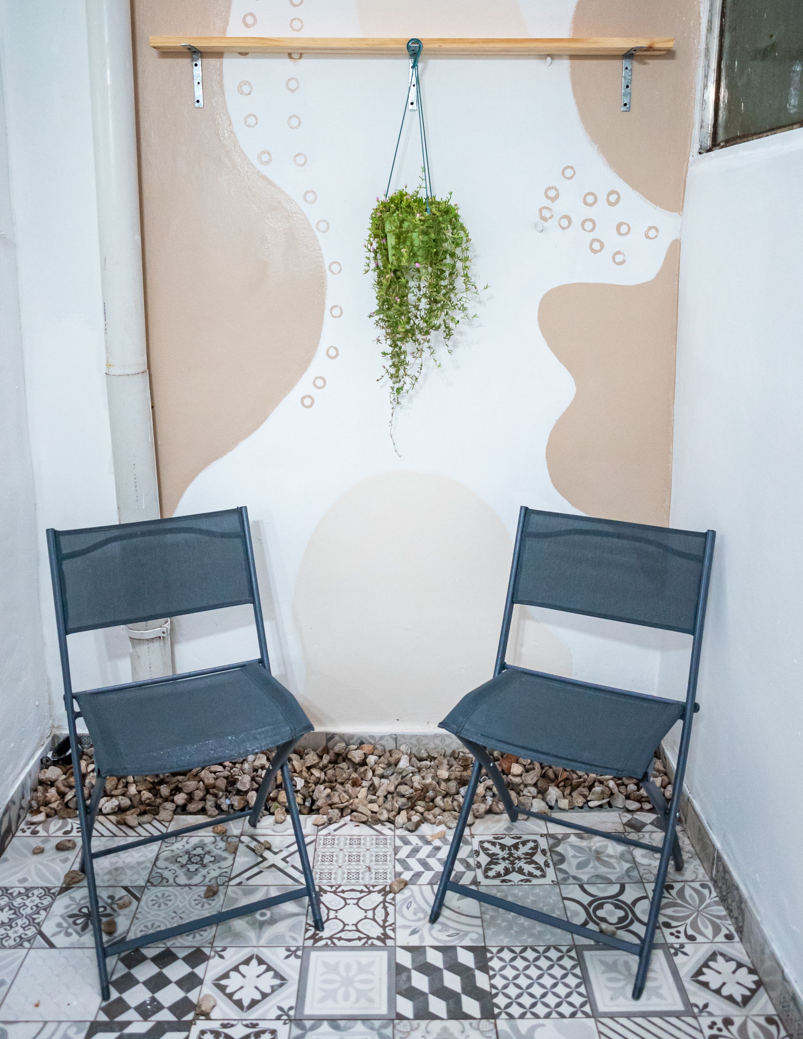 Small polyester hanging chair hanging from a small apartment patio ceiling at a railing