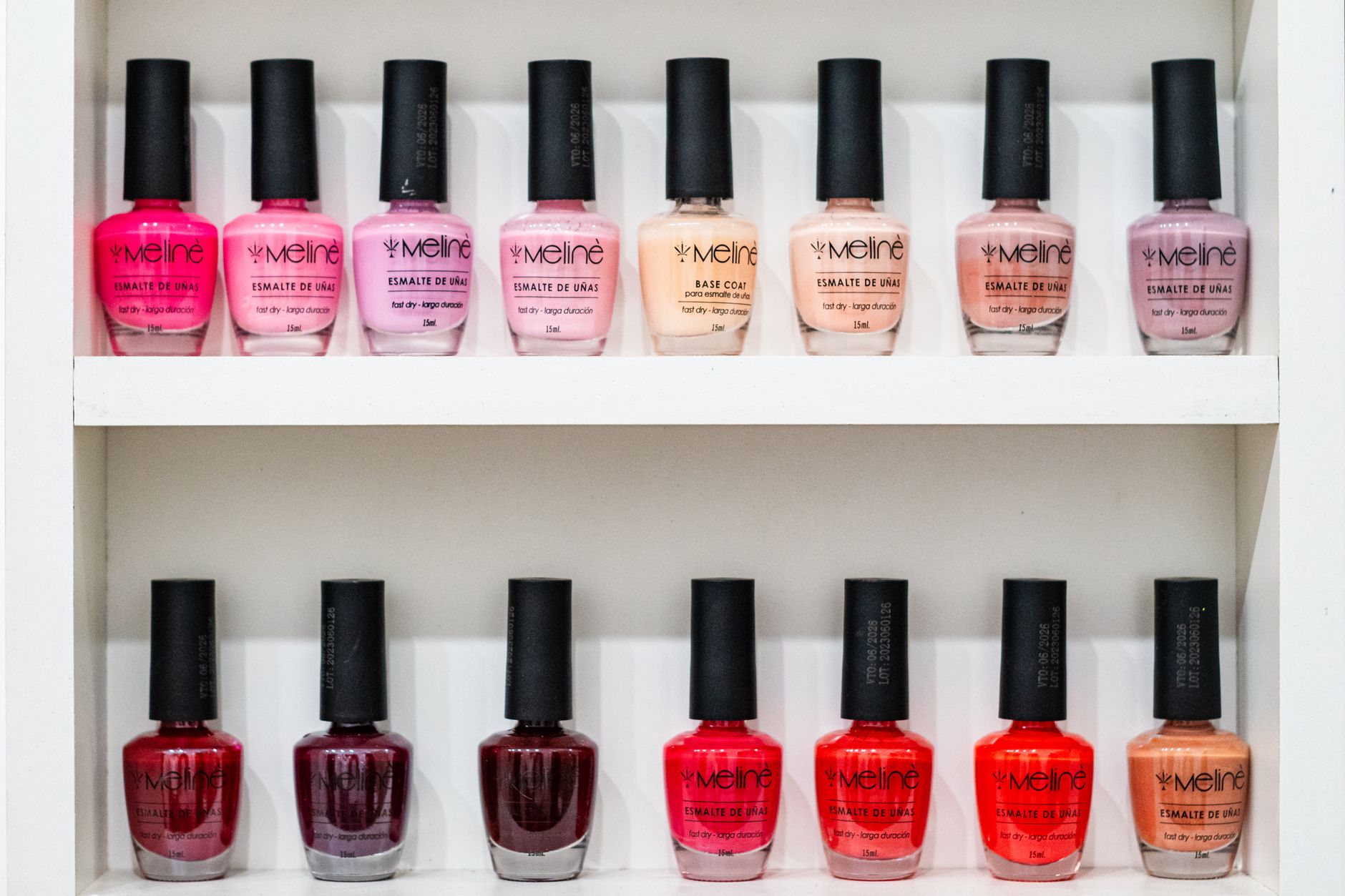 Vibrant display of nail polish in various shades on a white shelf.