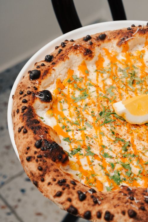 Free Mouth-watering gourmet pizza topped with fresh herbs and lemon slice, perfect for Italian cuisine lovers. Stock Photo