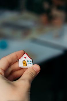 A hand holding a miniature house model with blurred background, symbolizing real estate or homeownership.