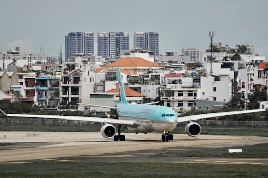 Airplane taxiing on runway at urban airport with cityscape in background.