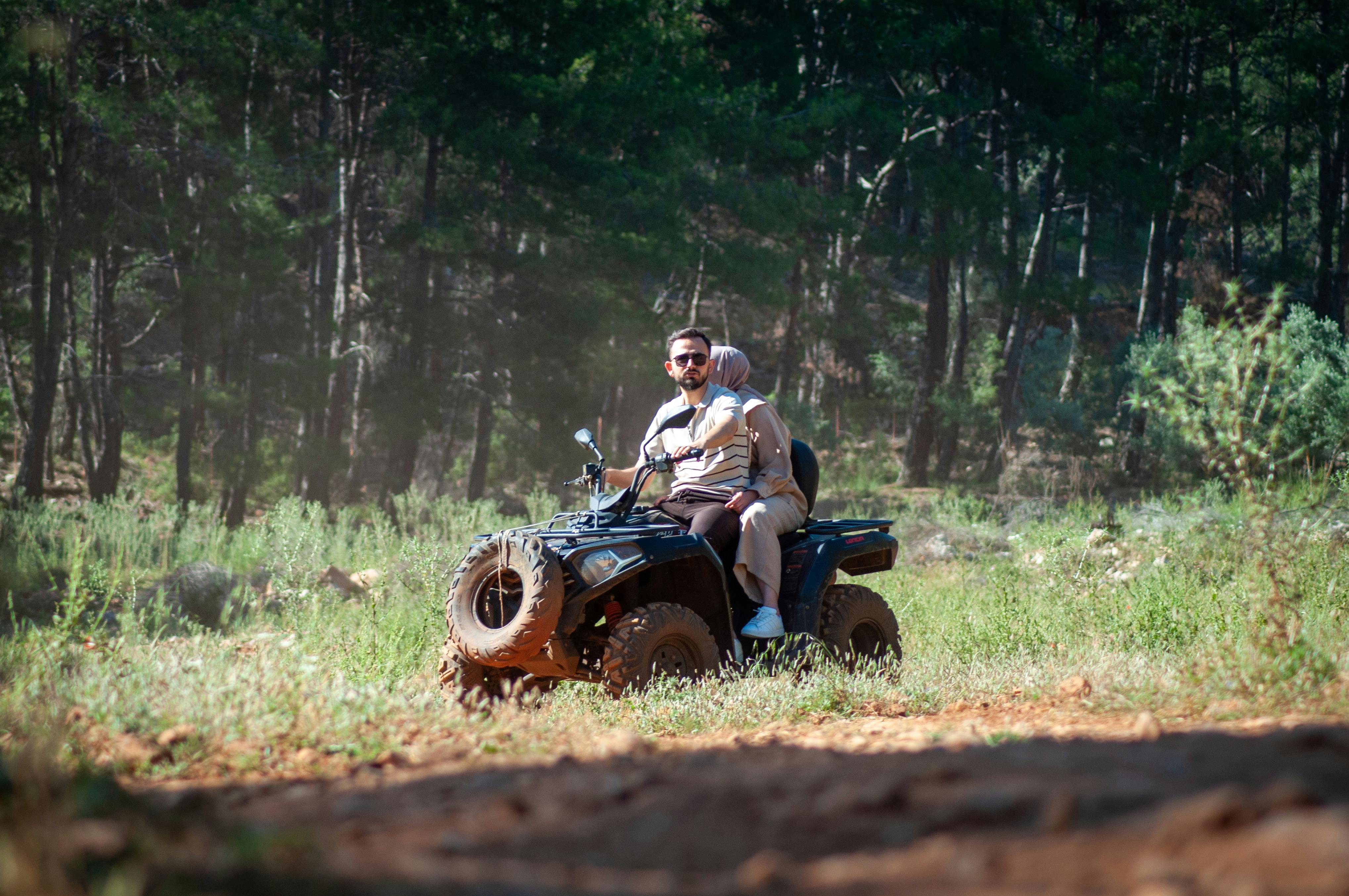 A couple enjoying an off-road adventure on an ATV in a lush Turkish forest. Perfect for travel and adventure themes.
