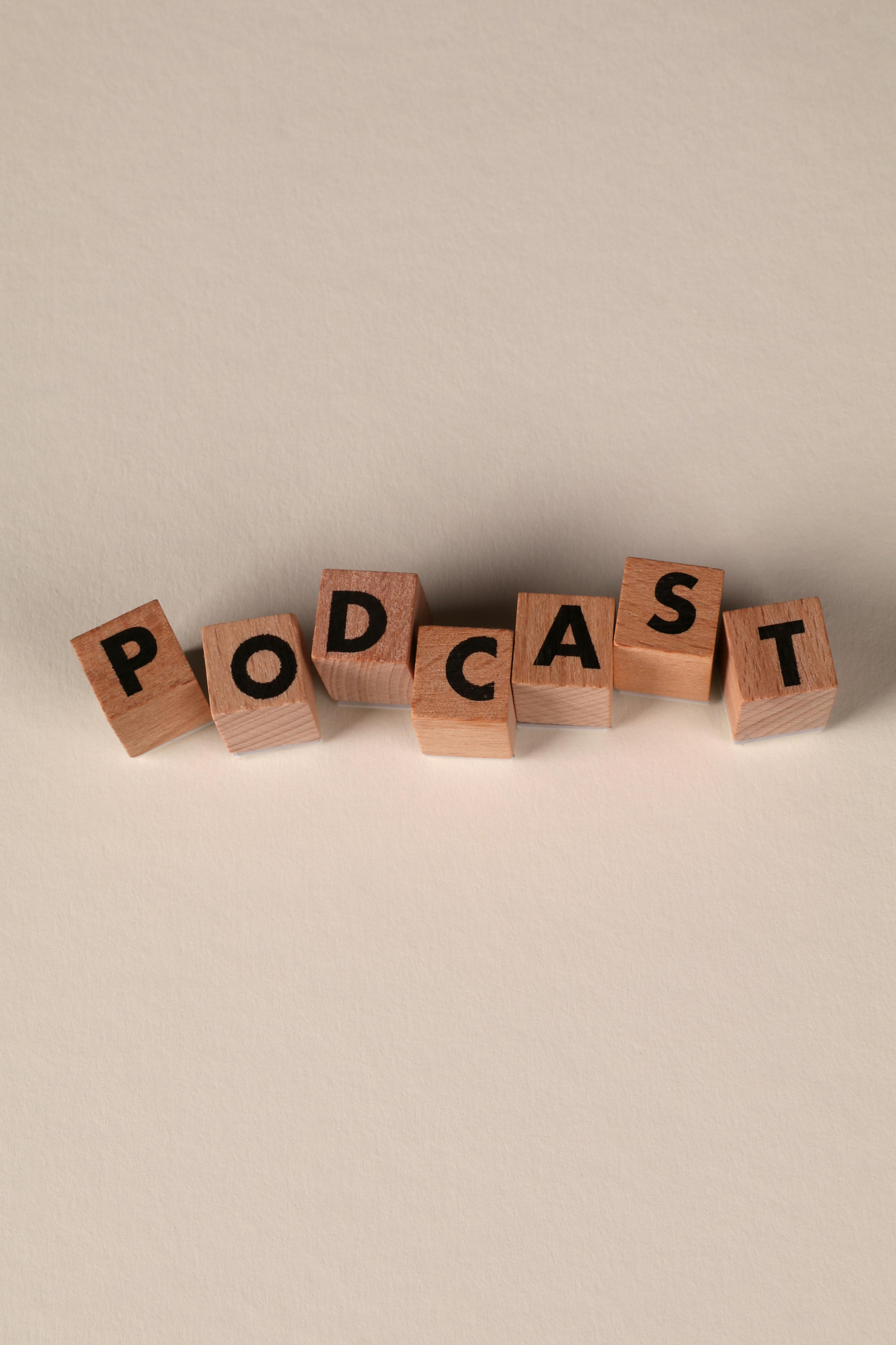 Gratis Blocchi di lettere in legno disposti a formare la parola "Podcast" su uno sfondo beige liscio. Foto a disposizione