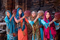 四名身着鲜艳传统服装的女性手持陶罐，展示文化遗产