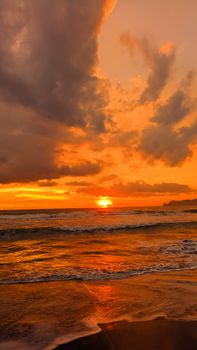 Vibrant sunset over Trenggalek Beach, Indonesia with dramatic clouds and waves.