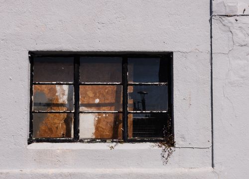 Free Rustic old industrial window with peeling paint on a cracked white wall. Urban decay concept. Stock Photo