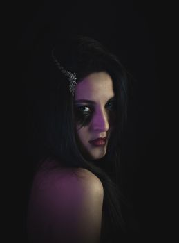 A mysterious and dramatic portrait of a woman with dramatic makeup in soft lighting.