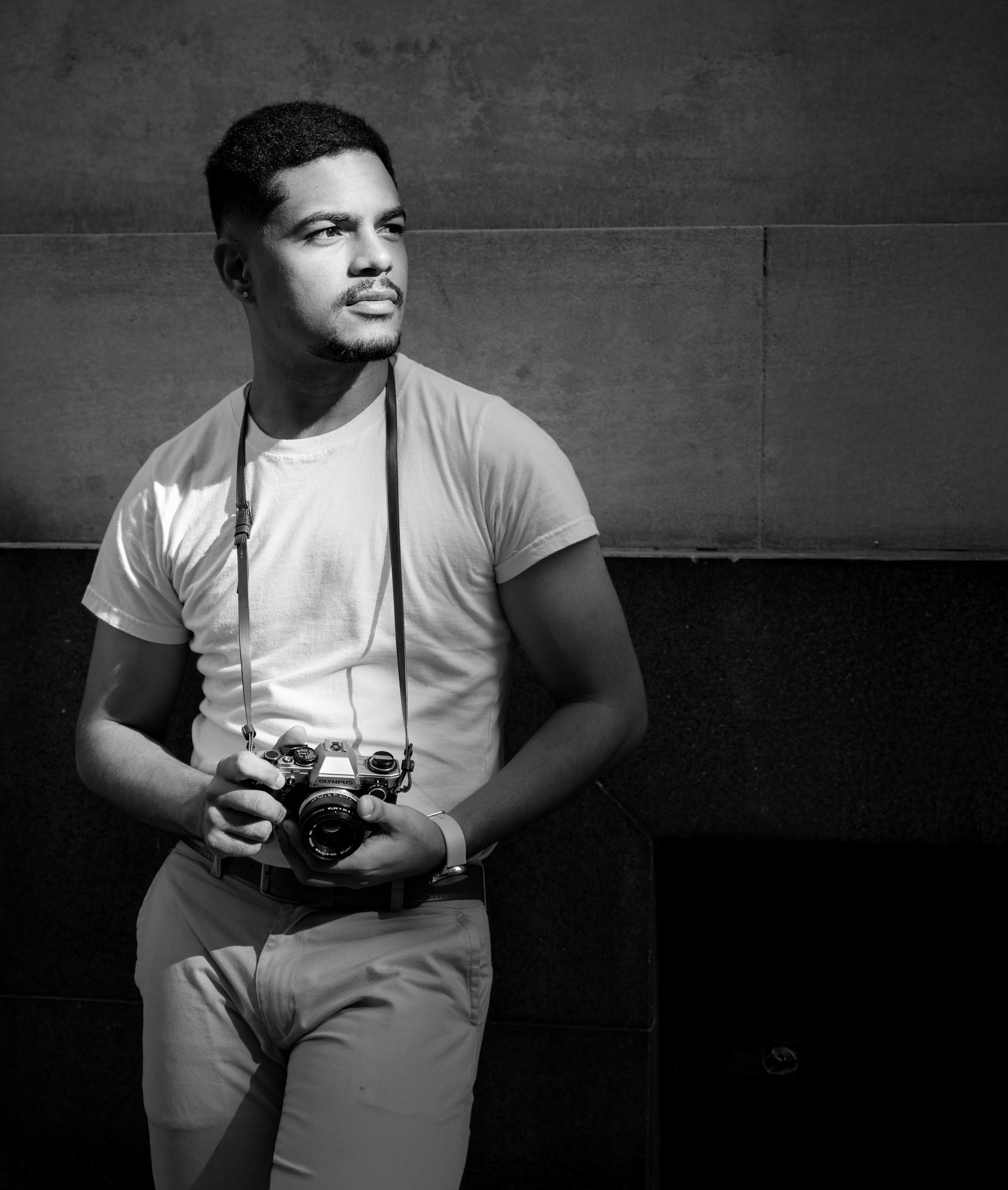 Stylish portrait of a photographer holding a camera in natural light.