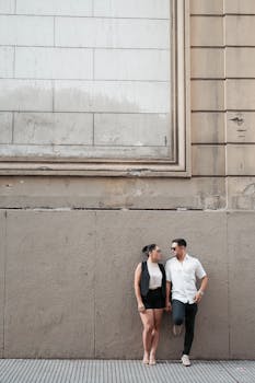 A couple leans against a historic wall in Buenos Aires, showcasing urban lifestyle.