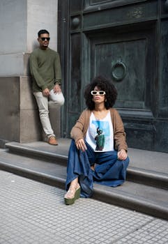 Two fashionable adults pose stylishly outdoors in Buenos Aires, showcasing modern urban fashion.