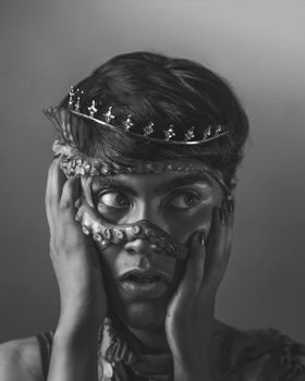 Black and white artistic portrait of a person with an octopus and tiara.