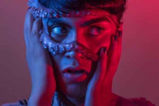 A dramatic portrait of a person wearing an octopus mask under vibrant neon lighting, evoking a surreal atmosphere.