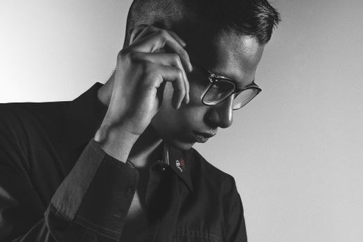 A monochrome portrait of a man in glasses exuding a contemplative mood, captured indoors.