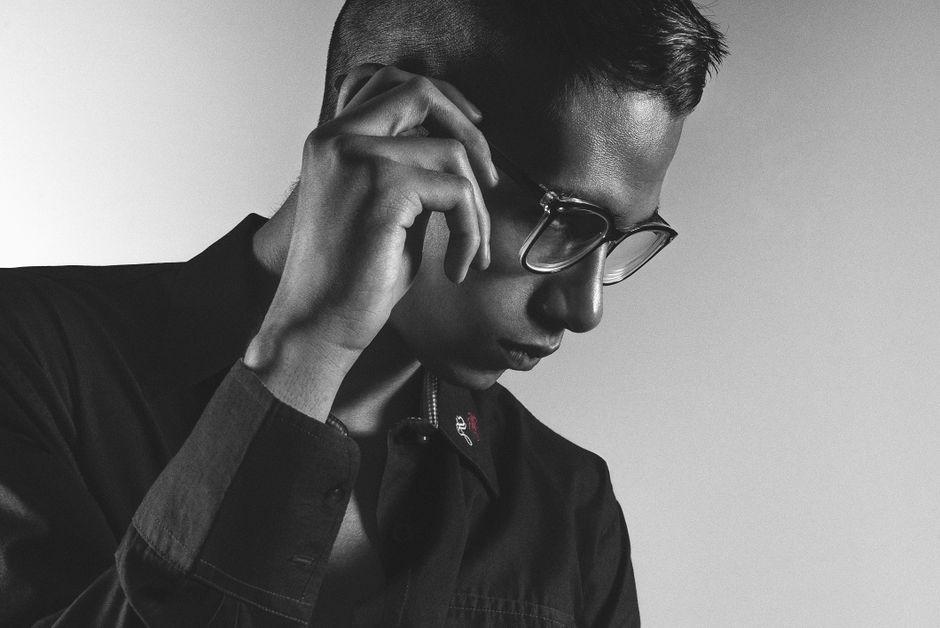 A monochrome portrait of a man in glasses exuding a contemplative mood, captured indoors.
