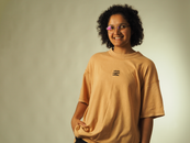 A smiling woman wearing glasses and a casual t-shirt poses joyfully.