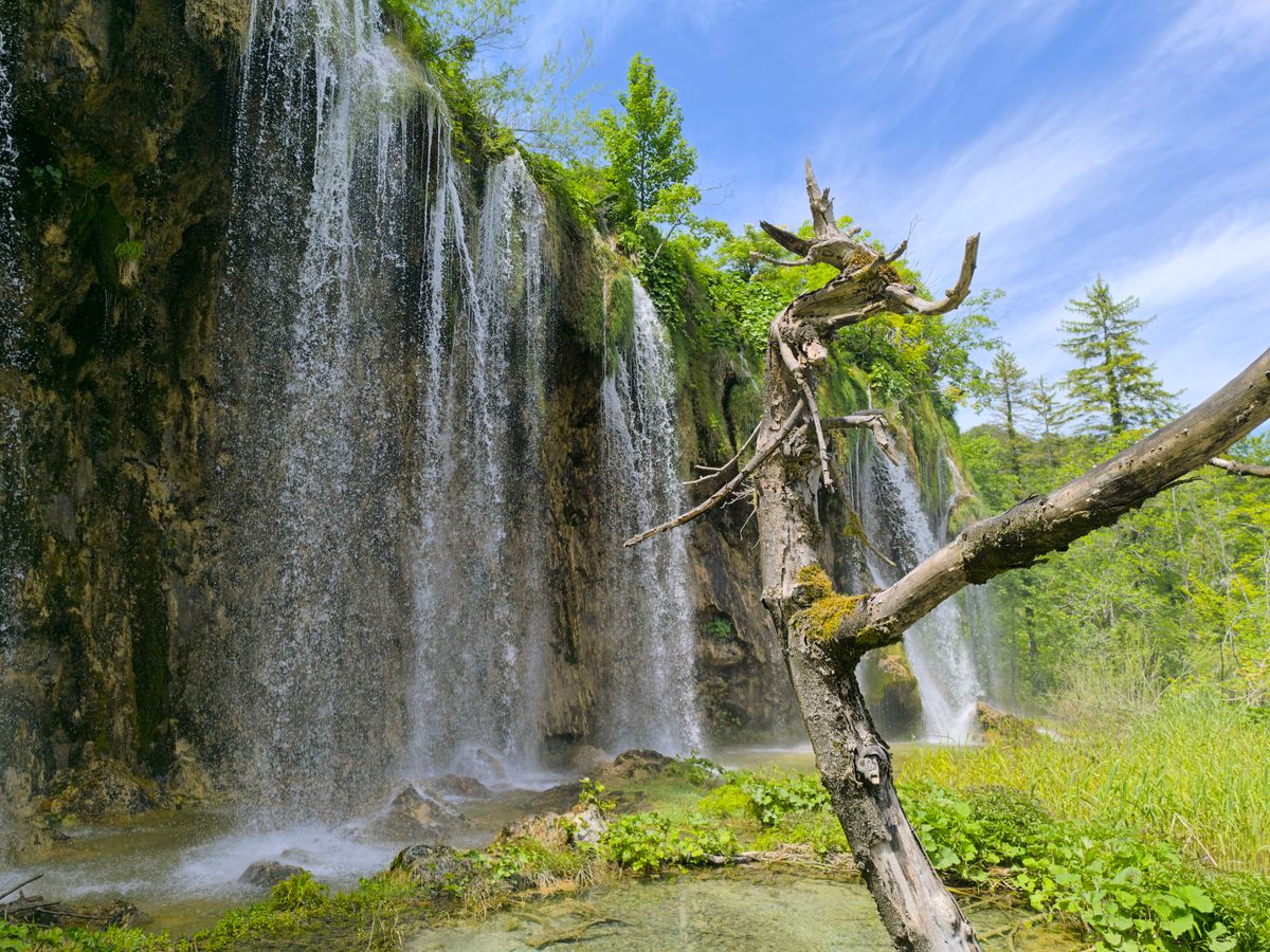 Waterfall cascading over rocks surrounded by lush greenery at Plitvice Lakes