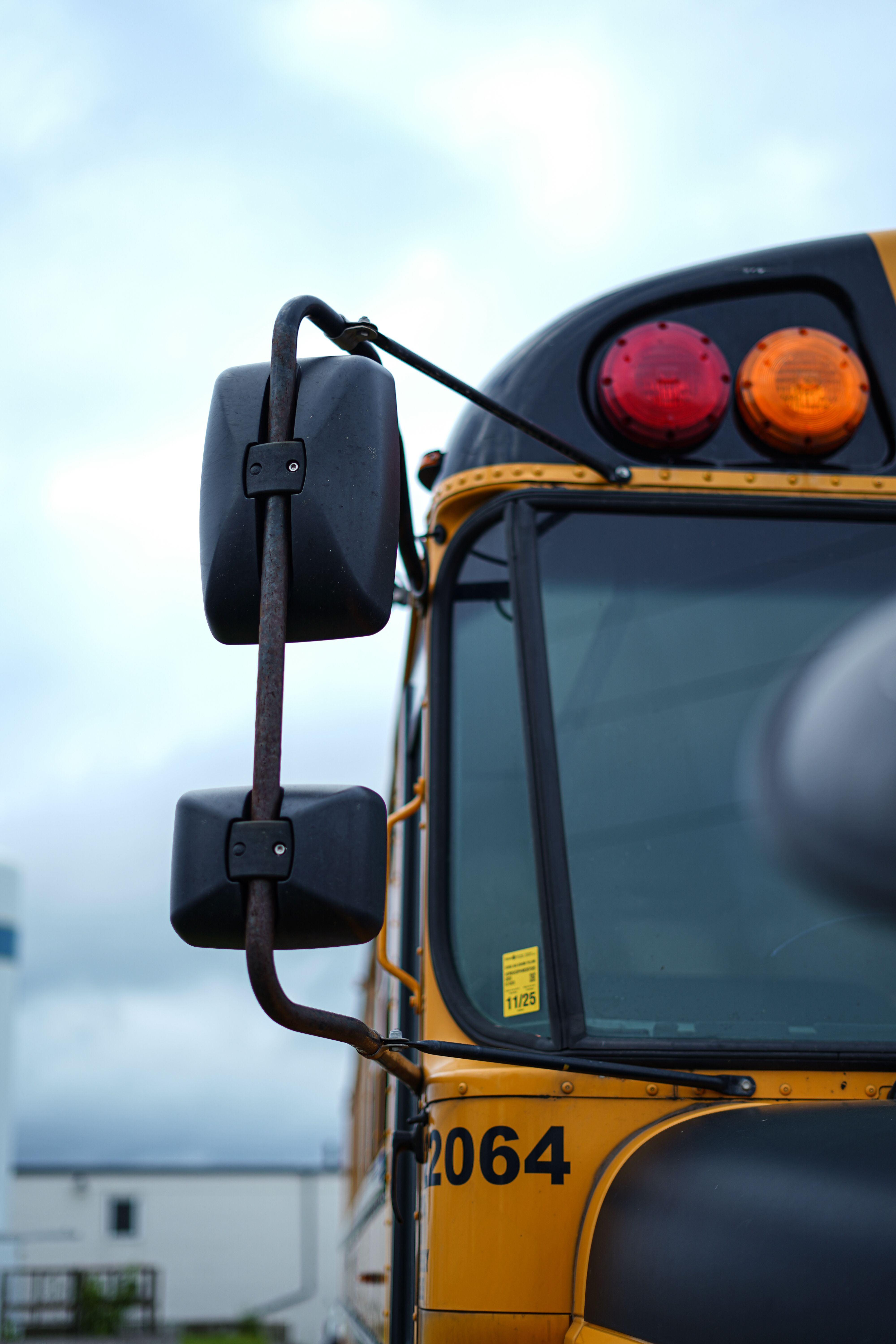 Detailed shot of a traditional yellow school bus mirror, emphasizing reflective design.