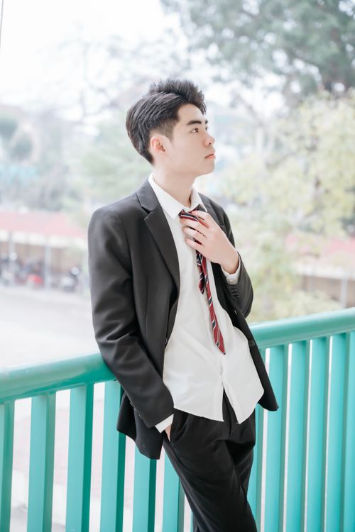 Free Young man dressed in a suit, relaxing on a balcony outdoors. Casual elegance. Stock Photo