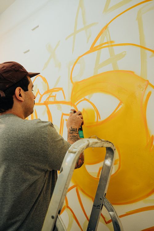 Free A young adult artist creating a colorful graffiti mural with spray paint indoors. Stock Photo