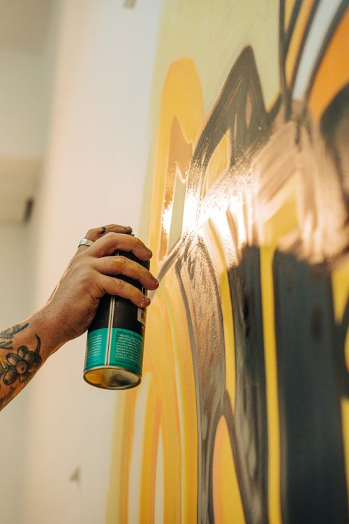 Free Close-up of a hand spray painting colorful graffiti on a wall. Stock Photo