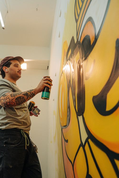 Free A street artist uses spray paint to create a colorful graffiti mural indoors. Stock Photo