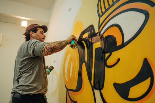 Free Artist passionately spray-painting vibrant graffiti on a wall indoors. Stock Photo