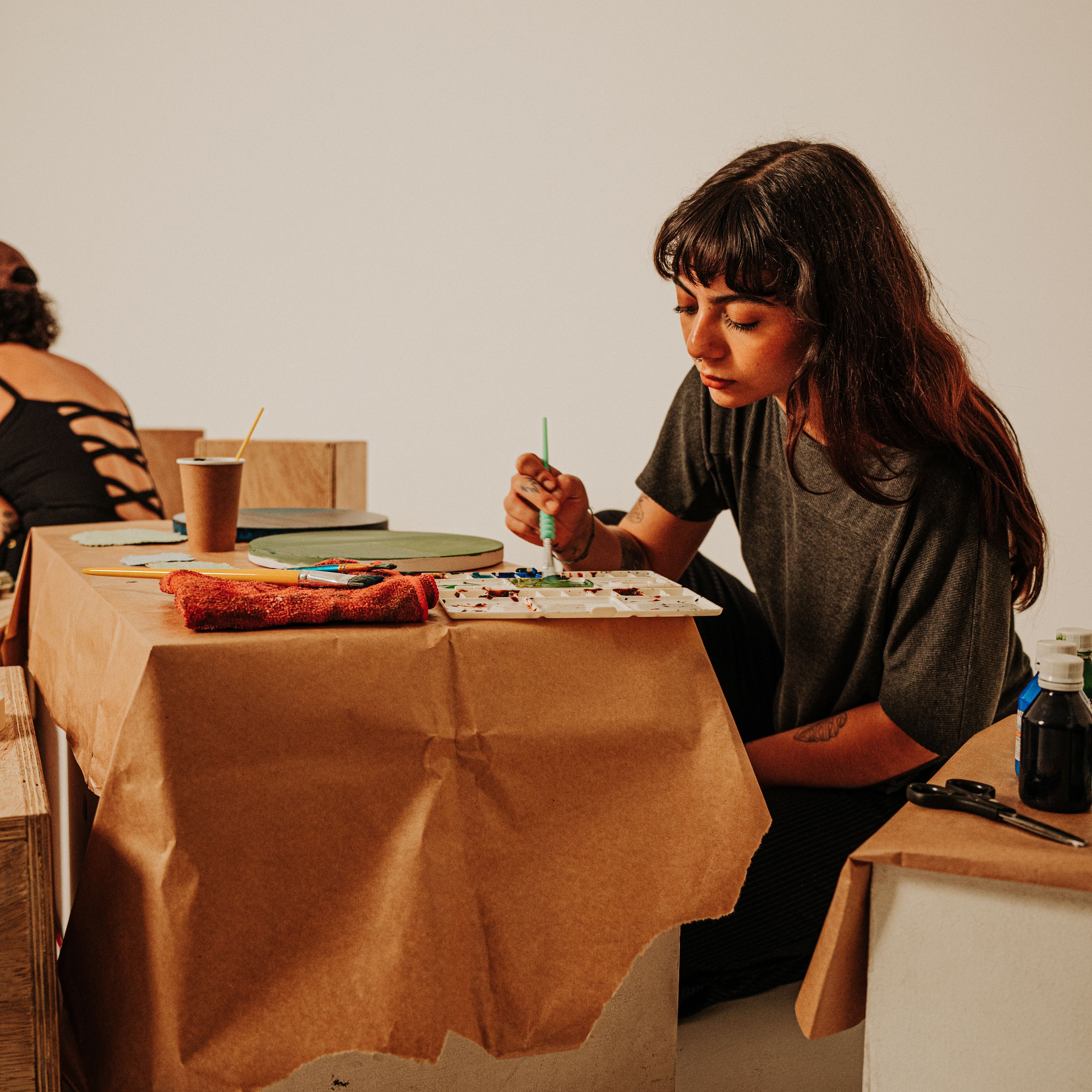 Young woman immersed in creating art in a cozy studio environment with vibrant colors.