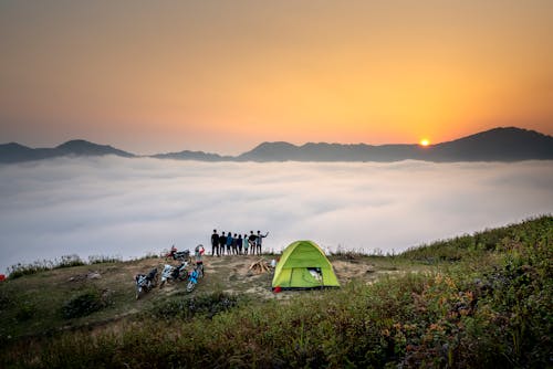 People Standing on Cliff Looking at Sea of Clouds