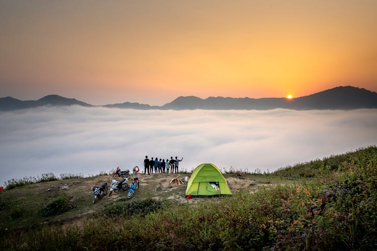 People Standing On Cliff Looking At Sea Of Clouds