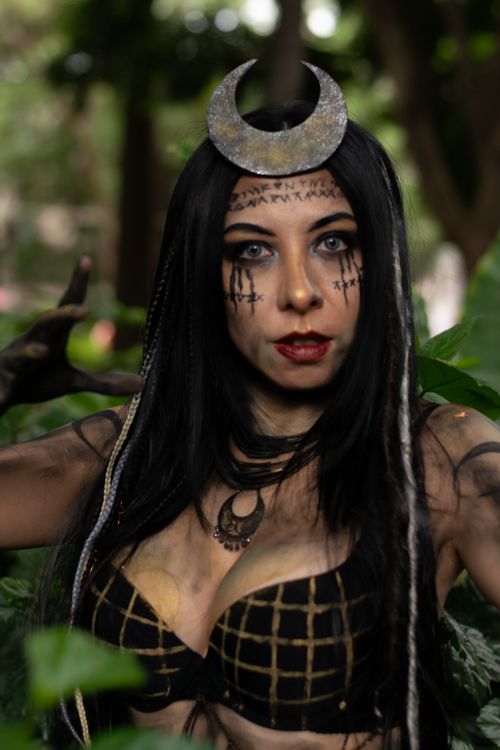 Free Dark-haired woman with moon headpiece in forest, exuding mystery and glamour. Stock Photo