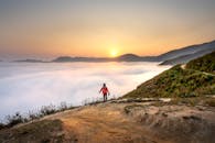 一名孤独的徒步旅行者站在山顶，惊叹于云层之上的日出