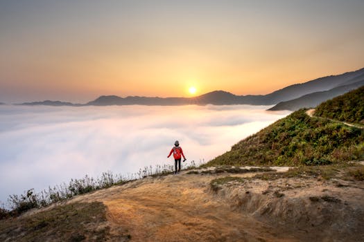 一名孤独的徒步旅行者站在山顶，惊叹于云层之上的日出