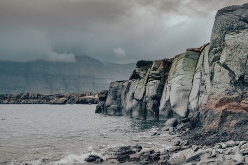 Free A moody photograph of rocky cliffs meeting the sea in Iceland, capturing the natural landscape and overcast skies. Stock Photo