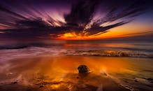 戏剧性的日落，色彩鲜艳，照亮了海洋和沙滩