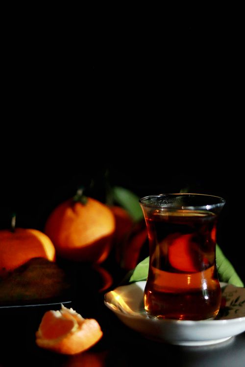 Free An aesthetic still life of tea served with fresh tangerines against a dark backdrop. Stock Photo