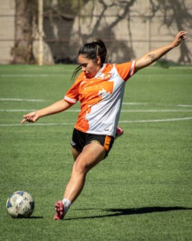 A young female athlete skillfully kicks a soccer ball during a sunny day on a sports field in Chile.