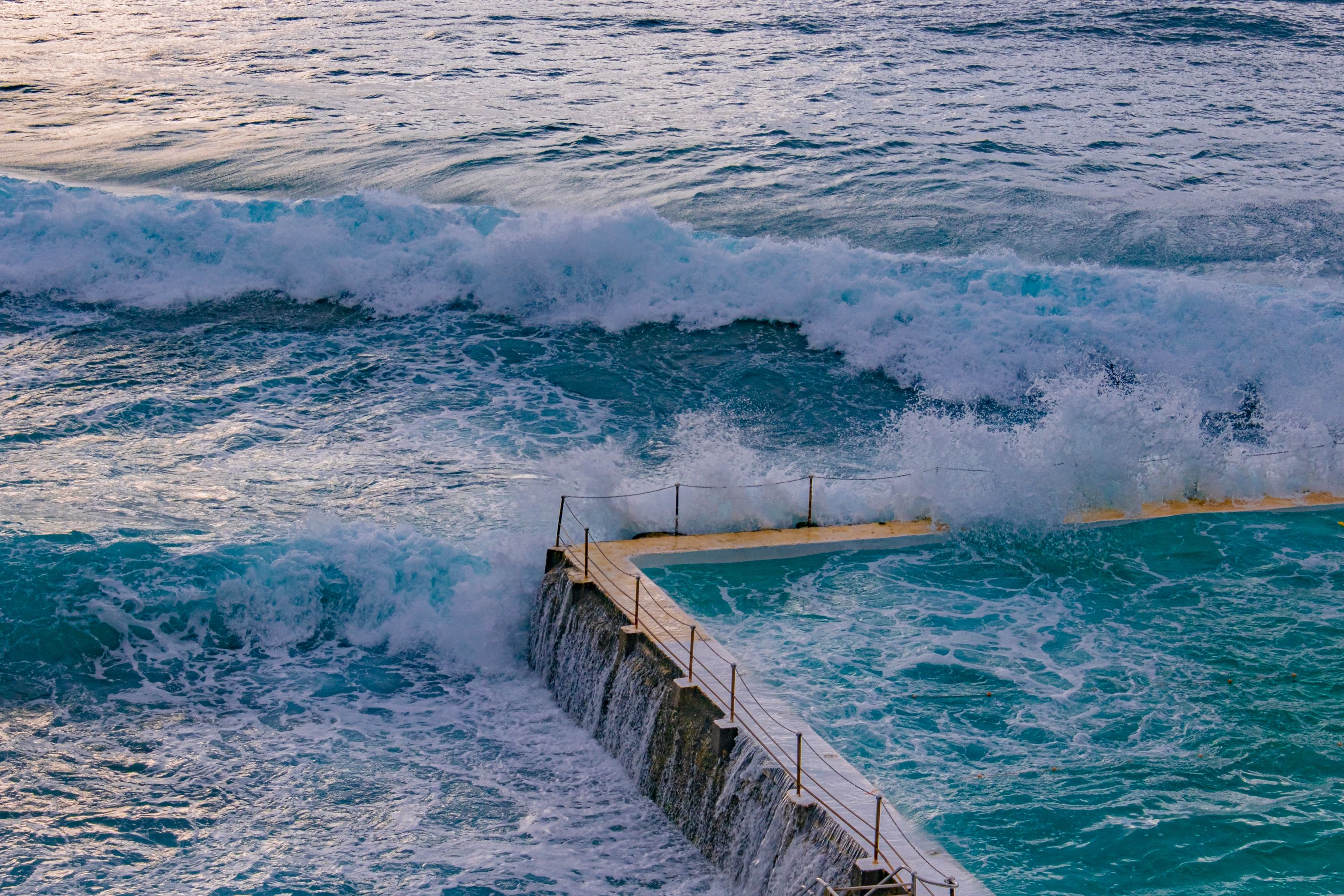 Stunning view of waves crashing over the ocean-facing pool in Bondi Beach, Sydney, Australia.