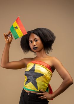 Portrait of woman holding Ghana flag in traditional attire. Celebratory vibe.