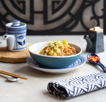 Asian fusion dish with noodles and tea set in a modern setting. Perfect for culinary enthusiasts.