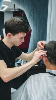 Barber focused on styling a client's hair with scissors in a contemporary salon setting.
