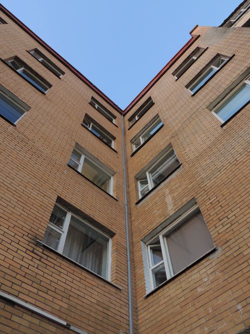 Free Low angle view of a brick building facade rising towards a clear blue sky on a sunny day. Stock Photo