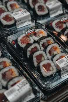Close-up of assorted sushi rolls in packaging, showcasing Japanese culinary art in a store setting.