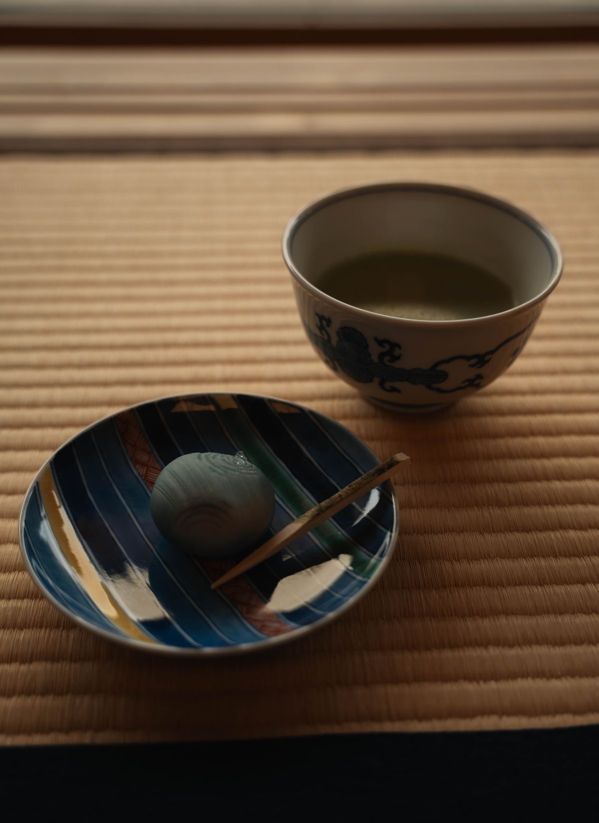 A bowl of frothy green matcha tea beside a delicate Japanese wagashi sweet on a tray