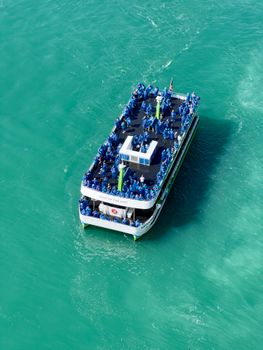 An aerial shot of the Maid of the Mist boat cruising the turquoise waters near Niagara Falls.