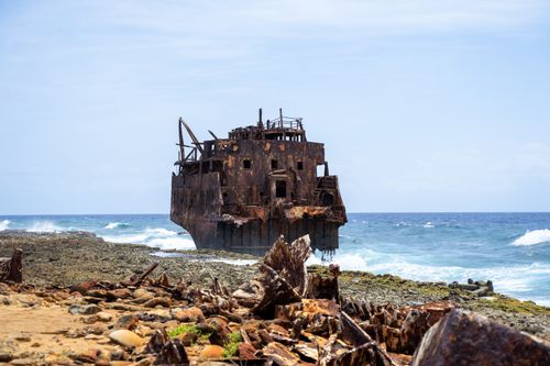 Free Discover a dramatic shipwreck on the rocky shores of Curaçao, captured under a bright sky. Stock Photo